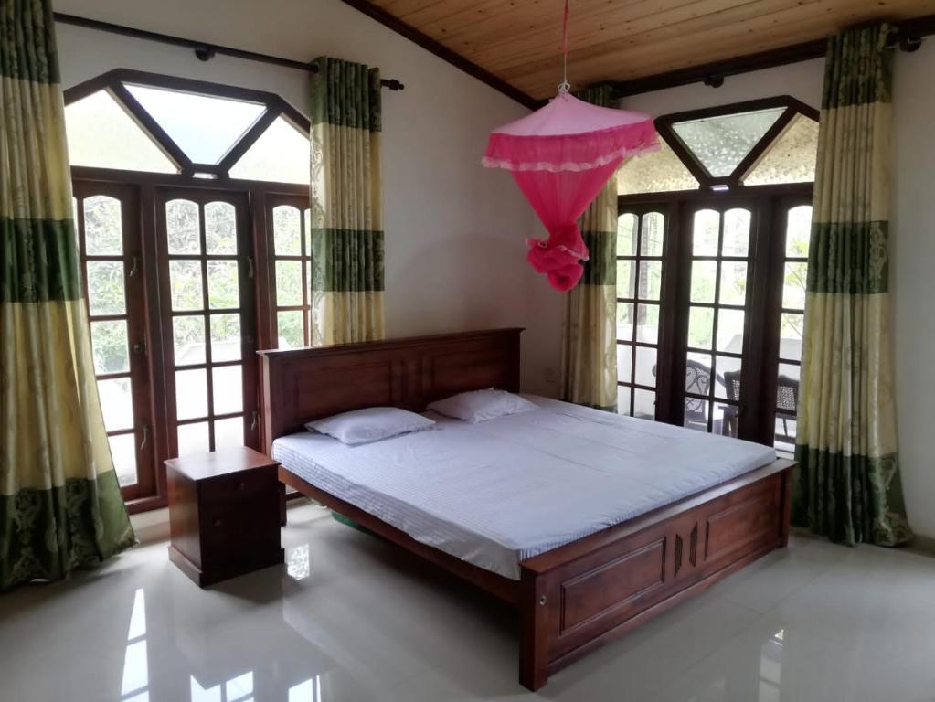 1 dormitorio con 1 cama con sombrilla rosa en Galle Side HomeStay en Galle