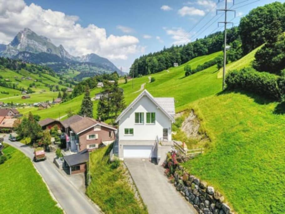 ein weißes Haus an der Seite eines grünen Hügels in der Unterkunft New Chalet with breathtaking views! in Alt Sankt Johann