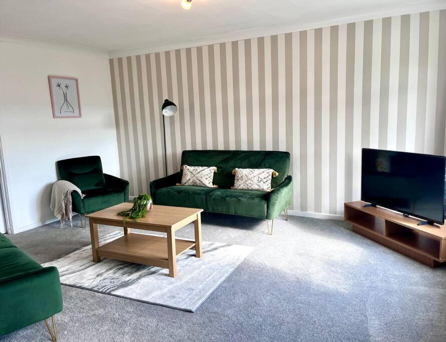 a living room with a green couch and a coffee table at Three bedroom house, close to airport, A1, NCL in Kenton