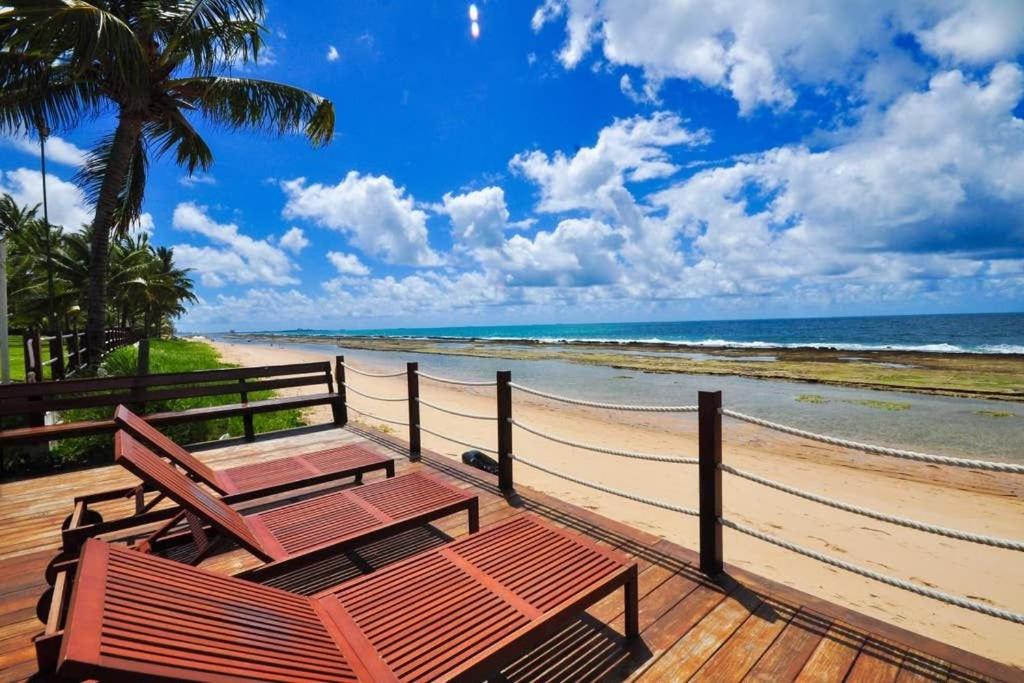a wooden deck with two tables and a beach at Flat 2302 - Flat no Beach Class Muro Alto 2 quartos - Praia de Muro Alto in Porto De Galinhas