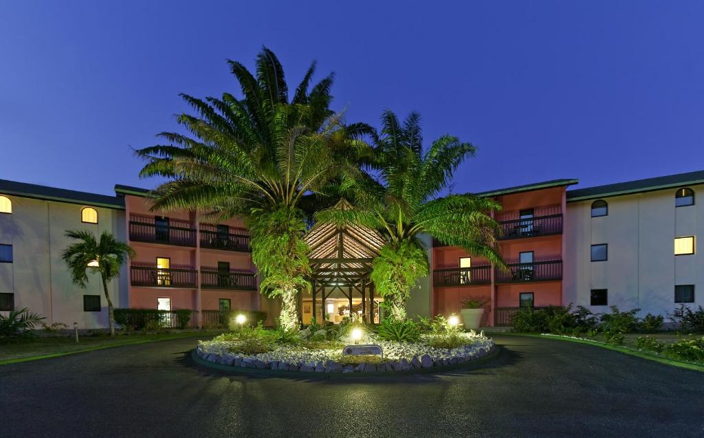 un edificio con dos palmeras delante en Grand Hotel Montabo, en Cayenne