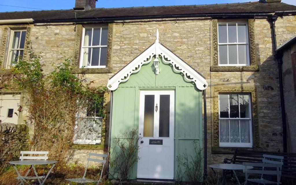 een groene deur aan de zijkant van een bakstenen huis bij Cherry Cottage, Youlgrave Nr Bakewell in Youlgreave