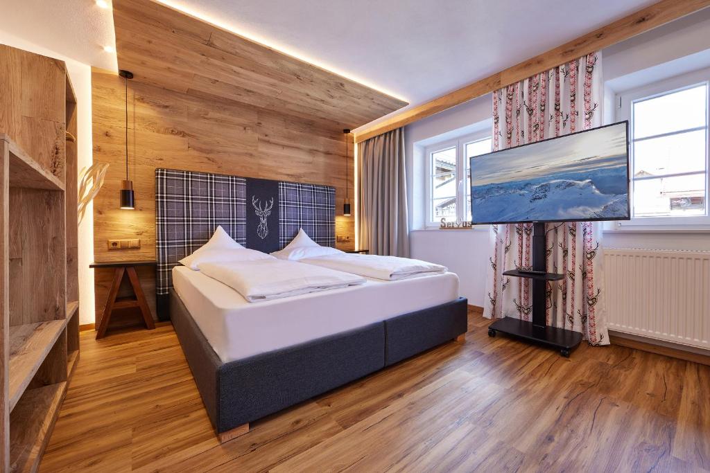 a bedroom with a bed and a flat screen tv at Gästehaus Angela in Garmisch-Partenkirchen