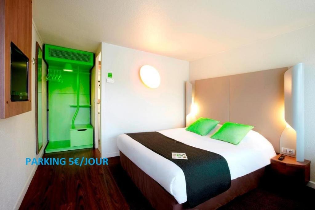 a hotel room with a large bed with green pillows at Campanile Rennes Ouest Cleunay in Rennes