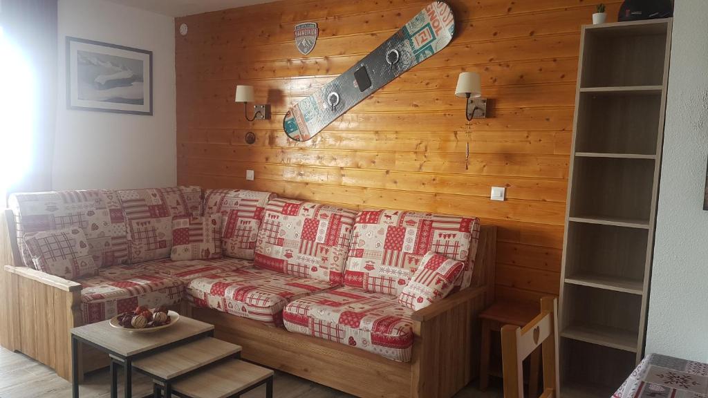 a living room with a couch with a snowboard on the wall at Chalet JL et DS , Pied des pistes, Valmeinier 1800, 10 pers. in Valmeinier