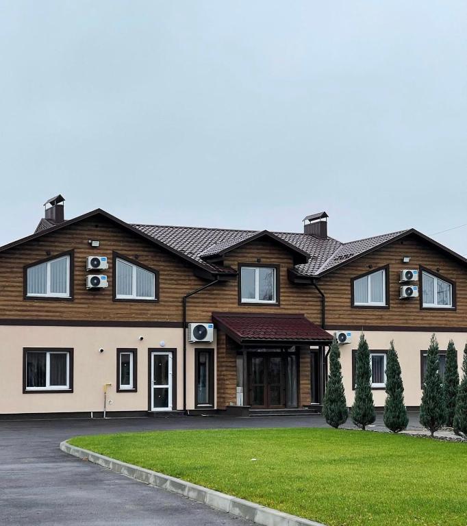 a large wooden house with a green lawn at Ні пуху, ні пера! in Reshetylivka