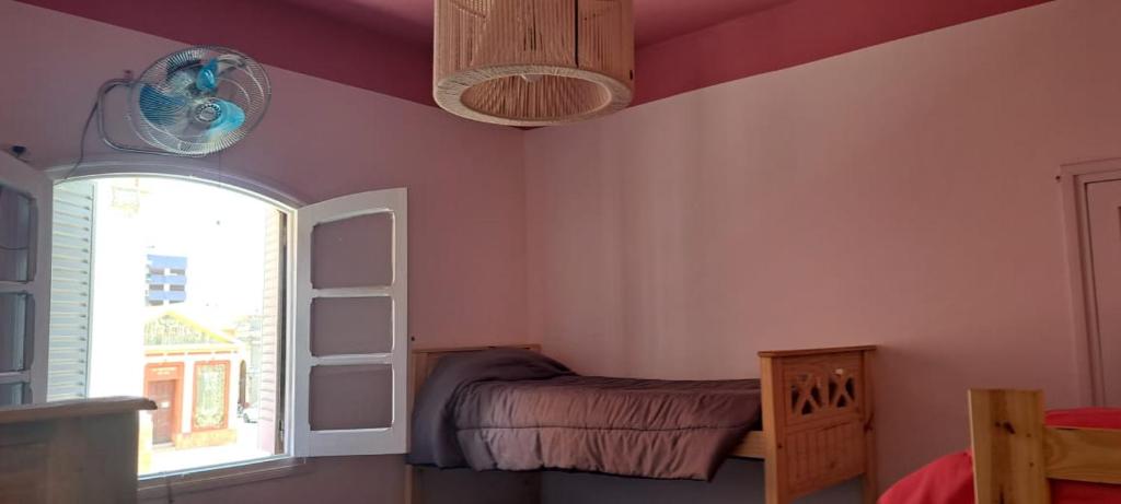 sypialnia z różowymi ścianami, oknem i łóżkiem w obiekcie Hostel LQueen 1 w mieście Salta