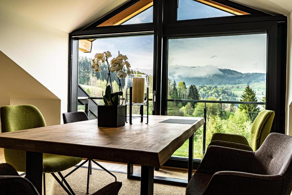une salle à manger avec une table et une grande fenêtre dans l'établissement Alpenloft Ausblick, à Oberstaufen