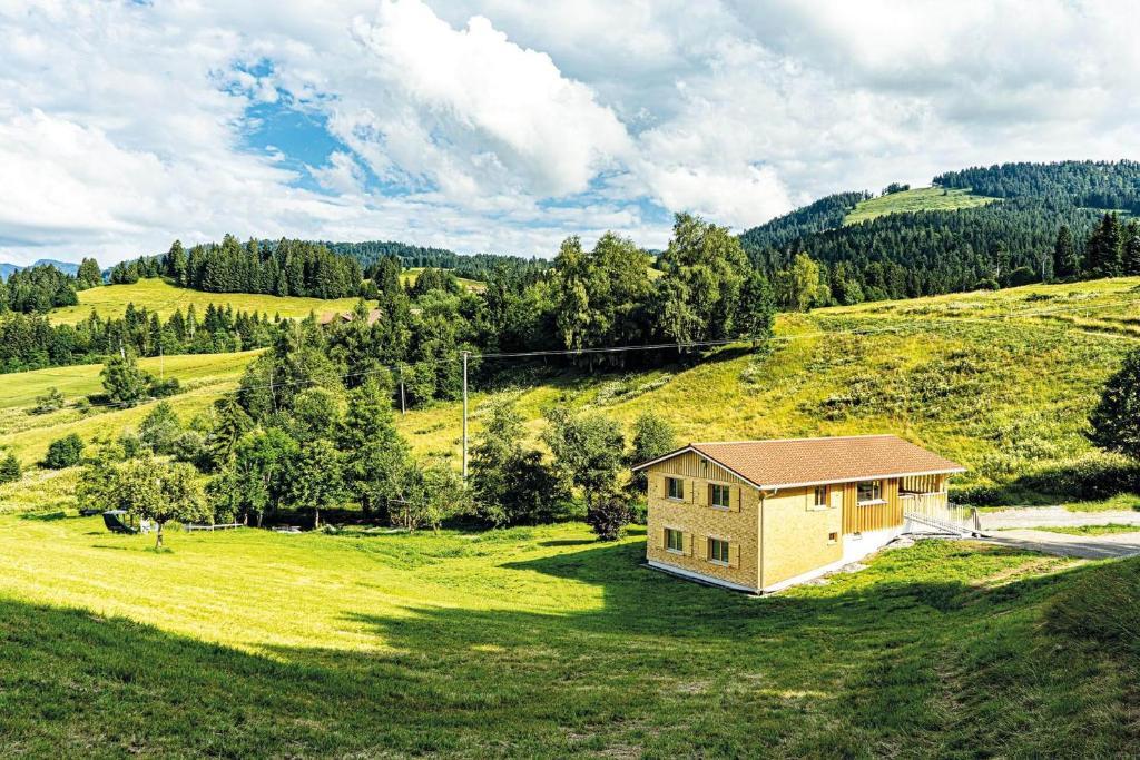 ein Haus auf einem Hügel mit einem grünen Feld in der Unterkunft Lohansler Hütte in Oberstaufen