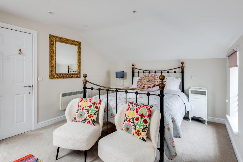 a bedroom with a bed with two chairs and a mirror at The Mews - 1BR Studio in Jericho near City Centre in Oxford