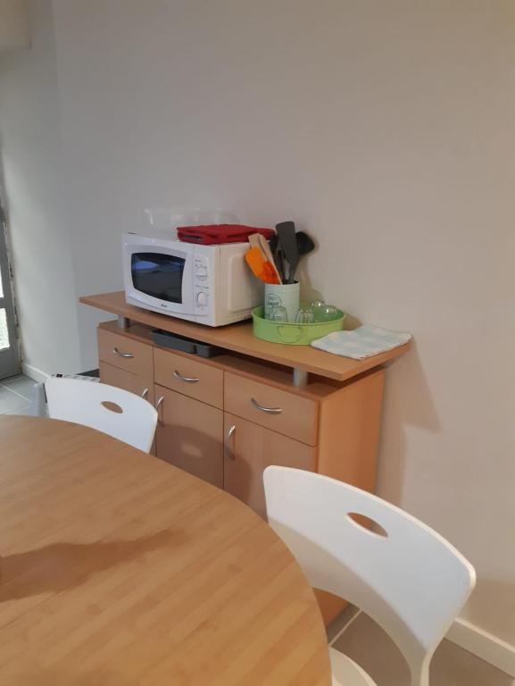 a table with two white chairs and a microwave at CHEZ ROSALIE 