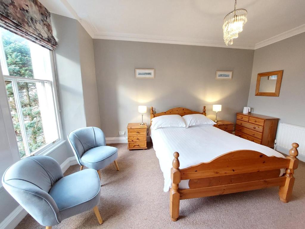 a bedroom with a large bed and a chair at Ashleigh House - Room Only in Windermere