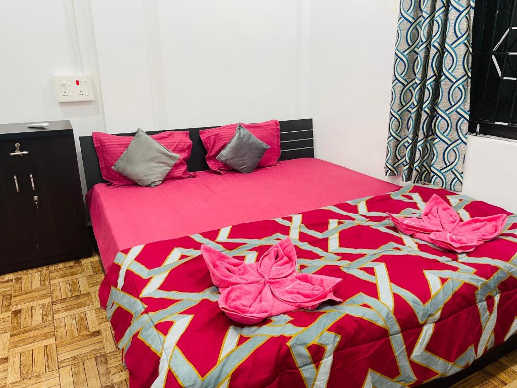 a bed with pink sheets and pink flowers on it at plefton guest house in Agonda