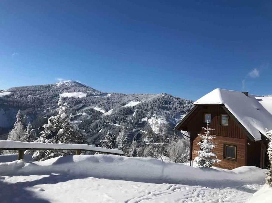 a cabin covered in snow with mountains in the background at Chalet Schröder in Klippitztorl