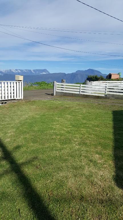 una cerca blanca frente a un campo de hierba en Case Vi d' o', en Le Tampon