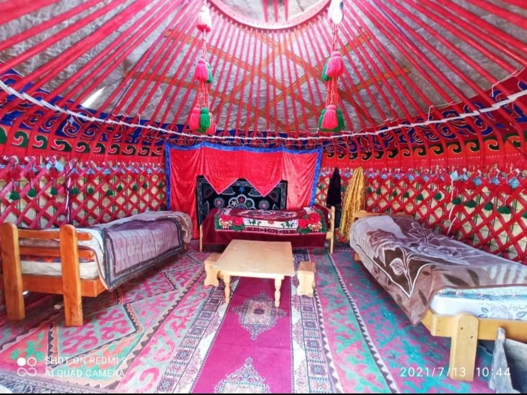 カラコルにあるKarakol Yurts Campのベッド2台とパオのテーブルが備わる部屋