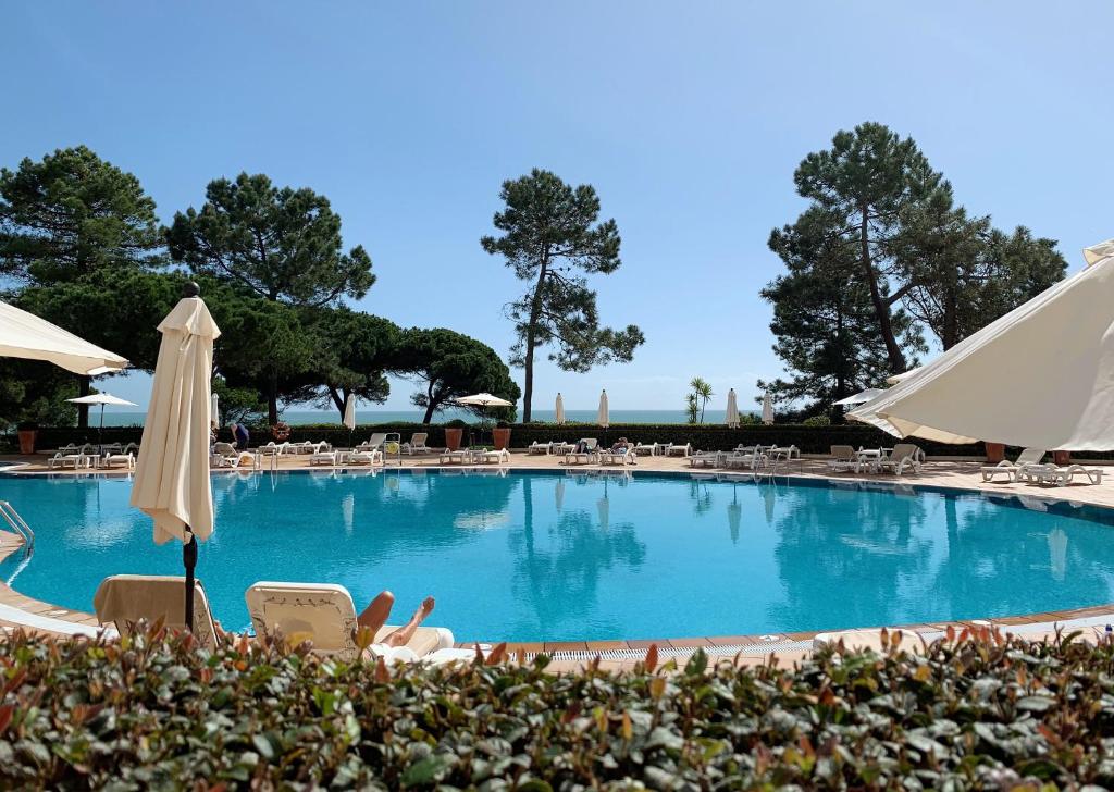 a large swimming pool with chairs and umbrellas at PortoBay Falesia in Albufeira