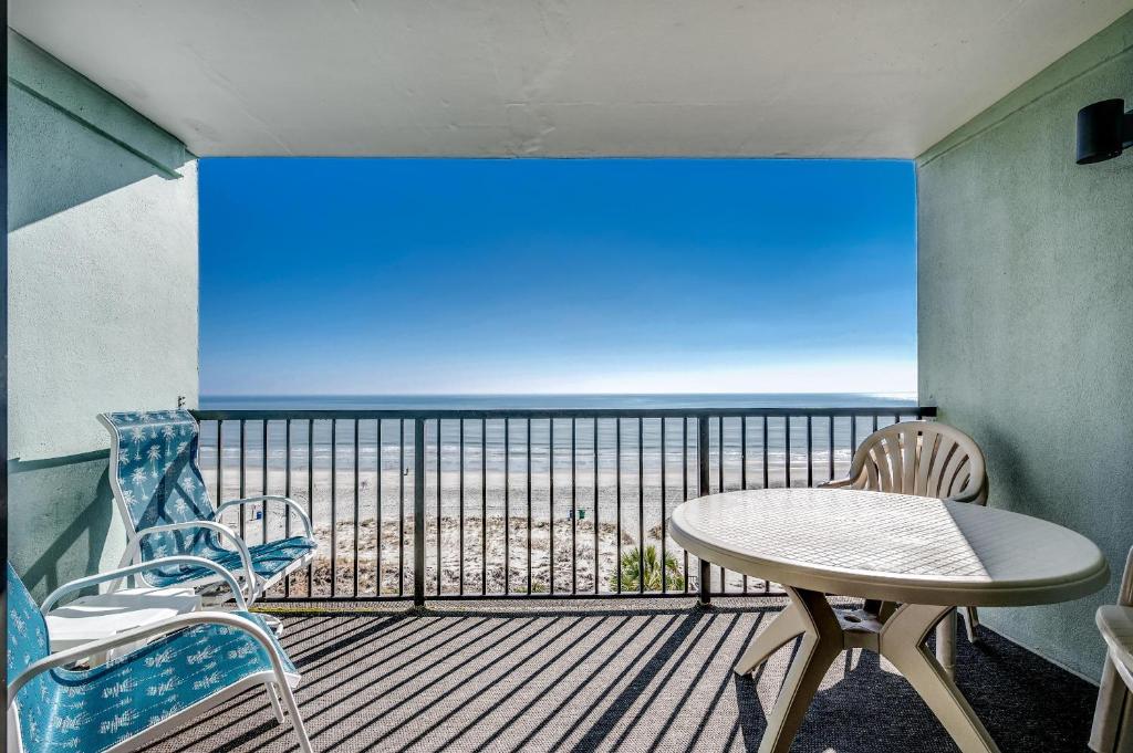a balcony with a table and chairs and a view of the ocean at Carolina Dunes - 503 in Myrtle Beach