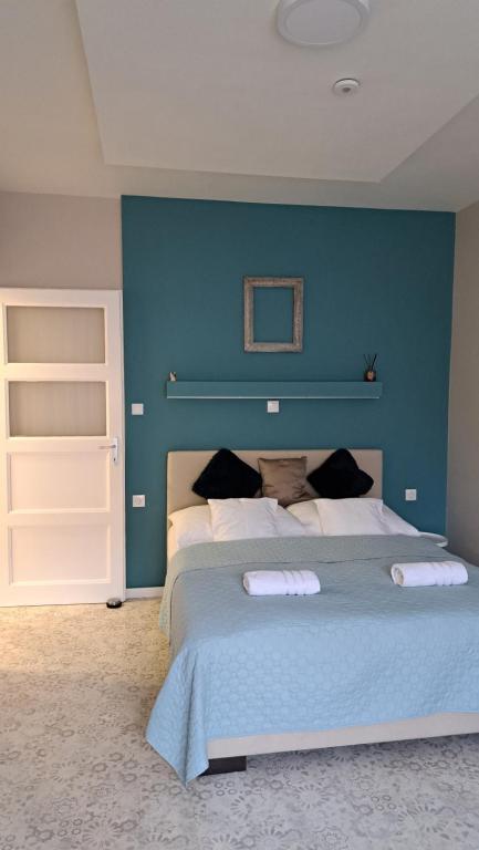 um quarto com uma parede azul e uma cama grande em Eper Apartman em Szeged