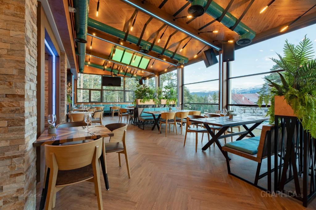 um restaurante com mesas e cadeiras e janelas grandes em 103 View Park Hotel & SPA em Panichishte