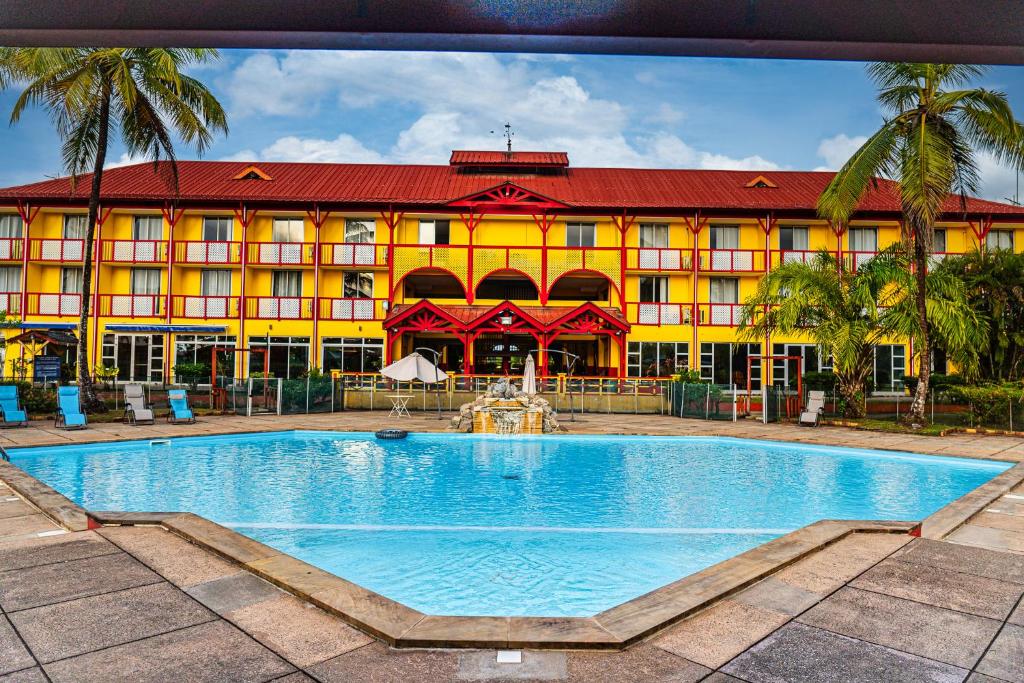 un hotel con piscina frente a un edificio en L'Hôtel Du Fleuve en Sinnamary