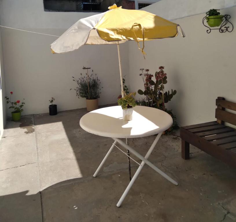 een witte tafel met een paraplu en enkele planten bij La estacion in Tandil