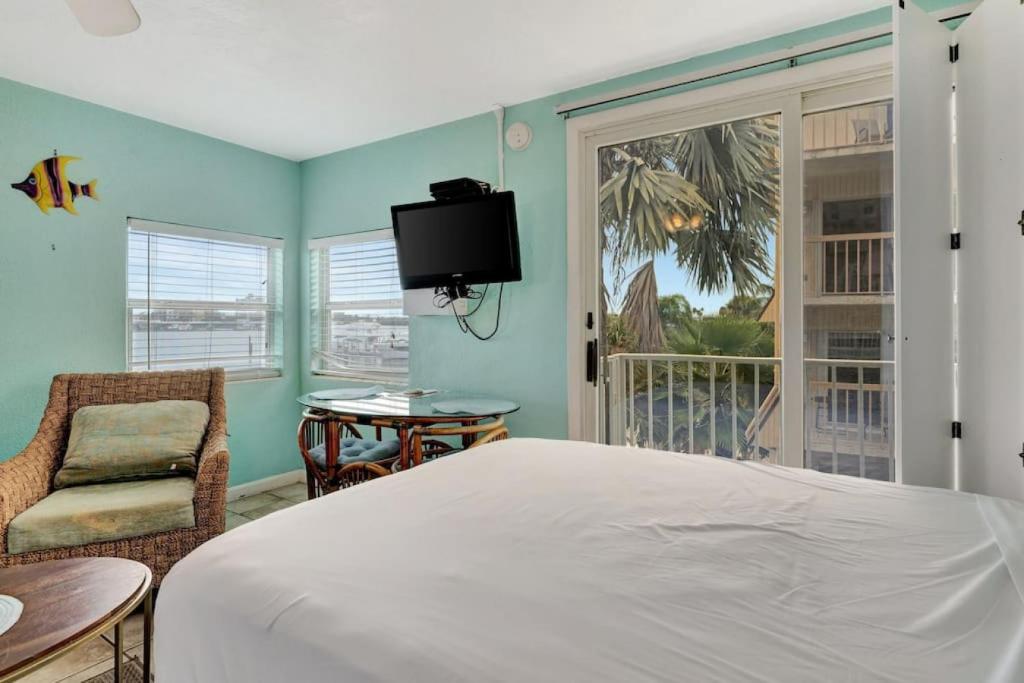 a bedroom with a bed and a chair and a window at The Seashell Suite with Private Balcony and Walk to Beach in Clearwater Beach