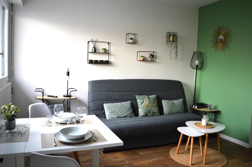 uma sala de estar com um sofá e uma mesa em Le Cocon de Nacre - à 300m de la plage - wifi em Courseulles-sur-Mer