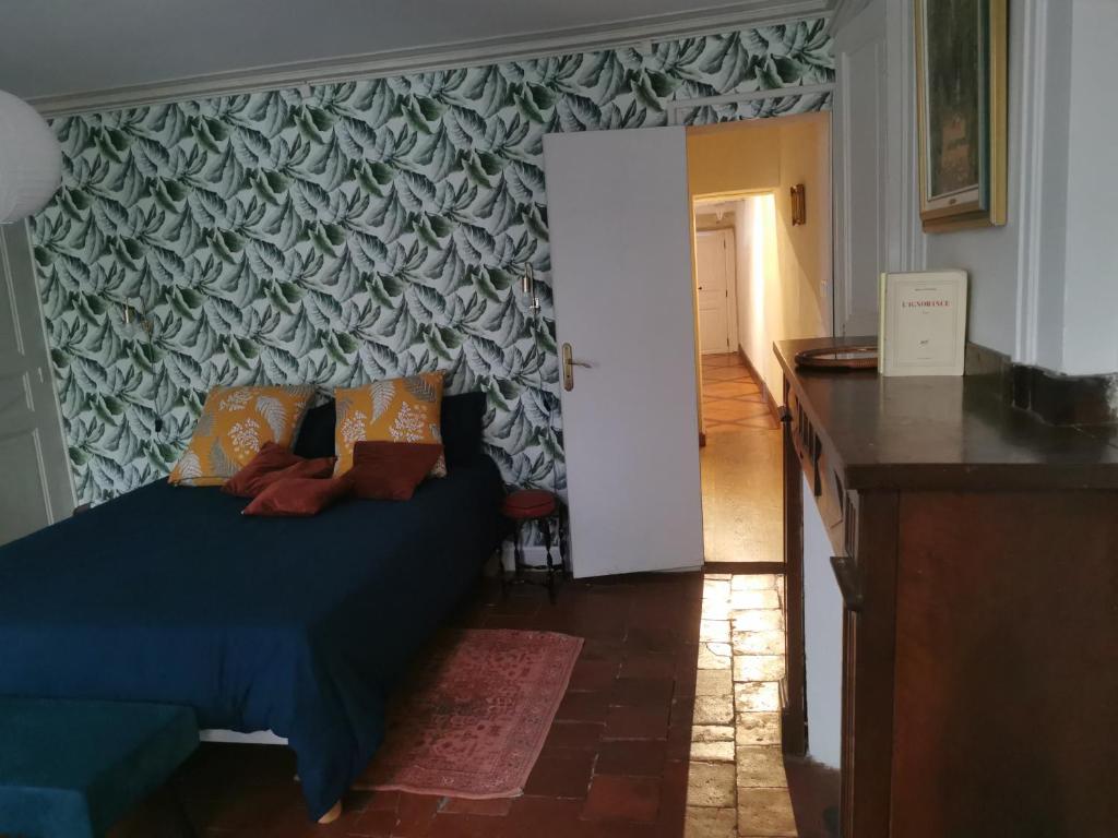 een slaapkamer met een blauw bed en een muur met patronen bij Alice & Jeanne - Chambre d'hôte in Lectoure