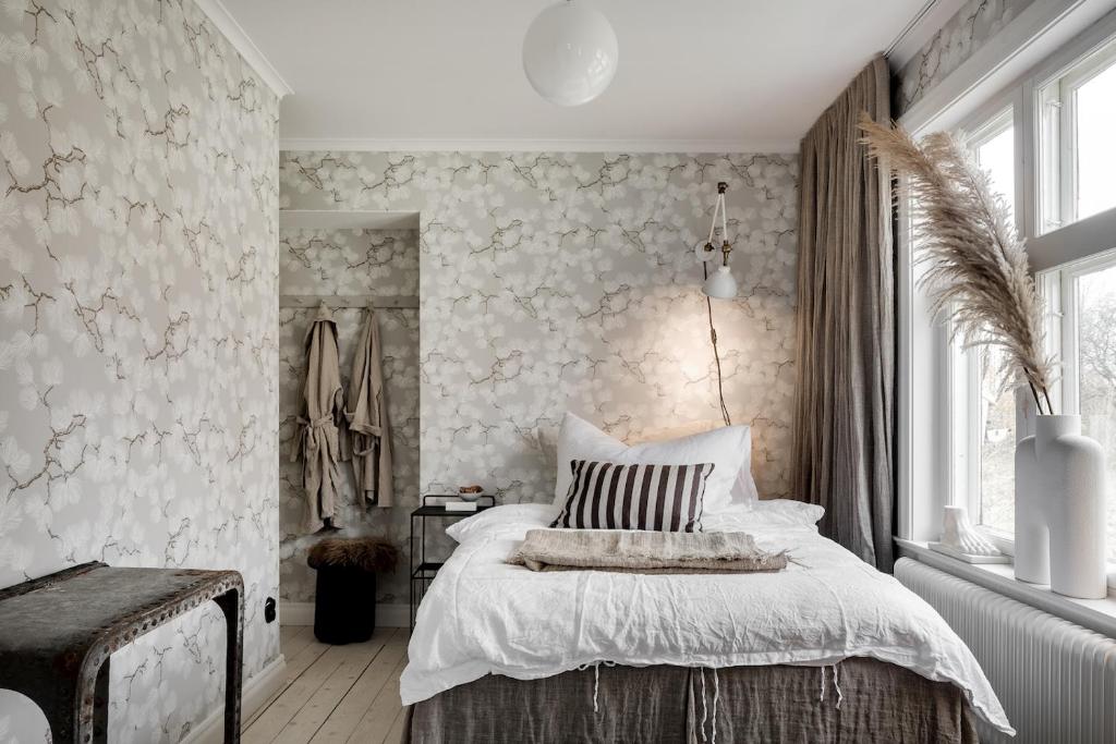 a bedroom with a bed and a wall with wallpaper at Bruket i Wiared in Borås