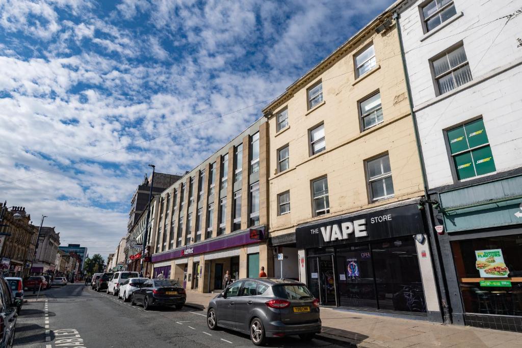 a street with cars parked on the side of a building at Market Square Apartments in Huddersfield