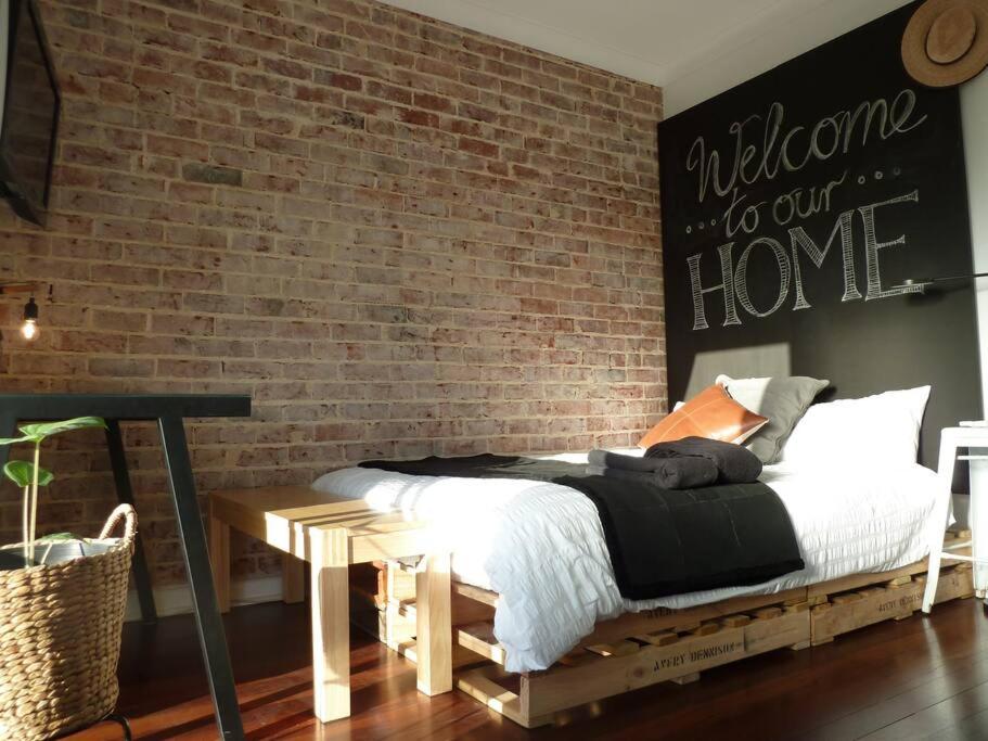 1 dormitorio con cama y pared de ladrillo en Studio A - Small Gem On The Busy Road, en Perth