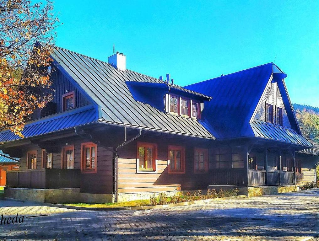 a large wooden house with a blue roof at Apartmány u Ivanky, Polanský dvůr 1149 in Velké Karlovice