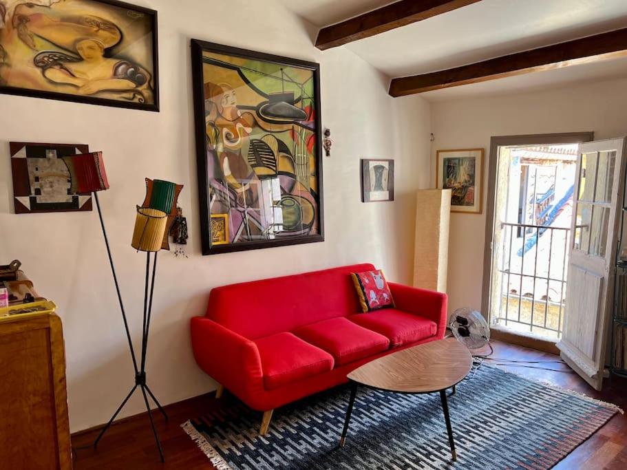 un soggiorno con divano rosso e tavolo di Une ambiance bohème sur les toits de Sainte-Anne a Montpellier