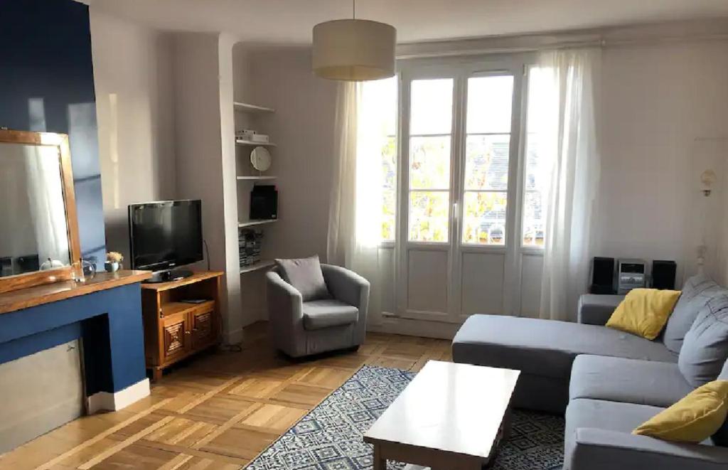 uma sala de estar com um sofá e uma televisão em Le Bleu Roi - Appartement calme proche de la Gare em Caen