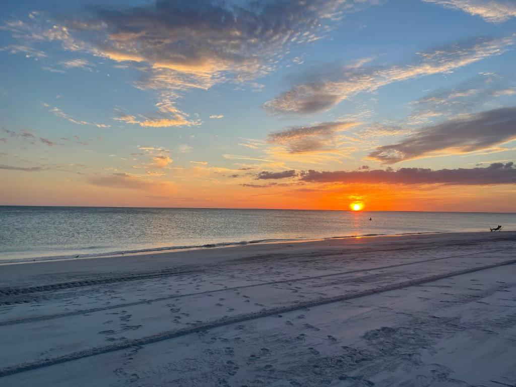 a sunset on a beach with a person walking on the sand at Sea Club I in Longboat Key