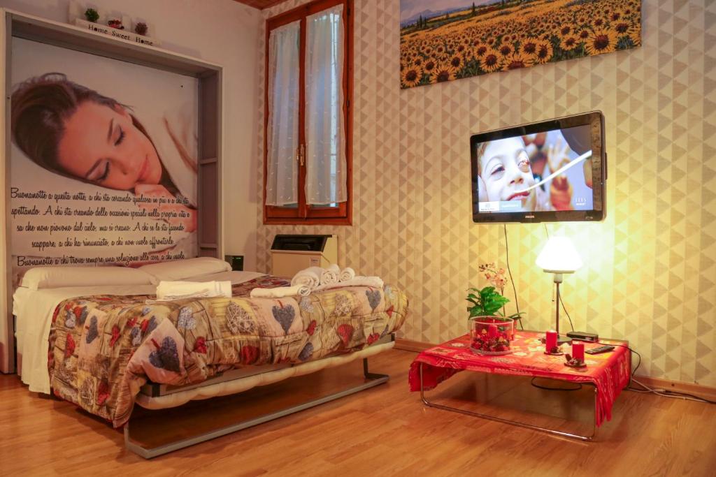 1 dormitorio con 1 cama y TV en la pared en Guest House Benny, en Reggio Emilia