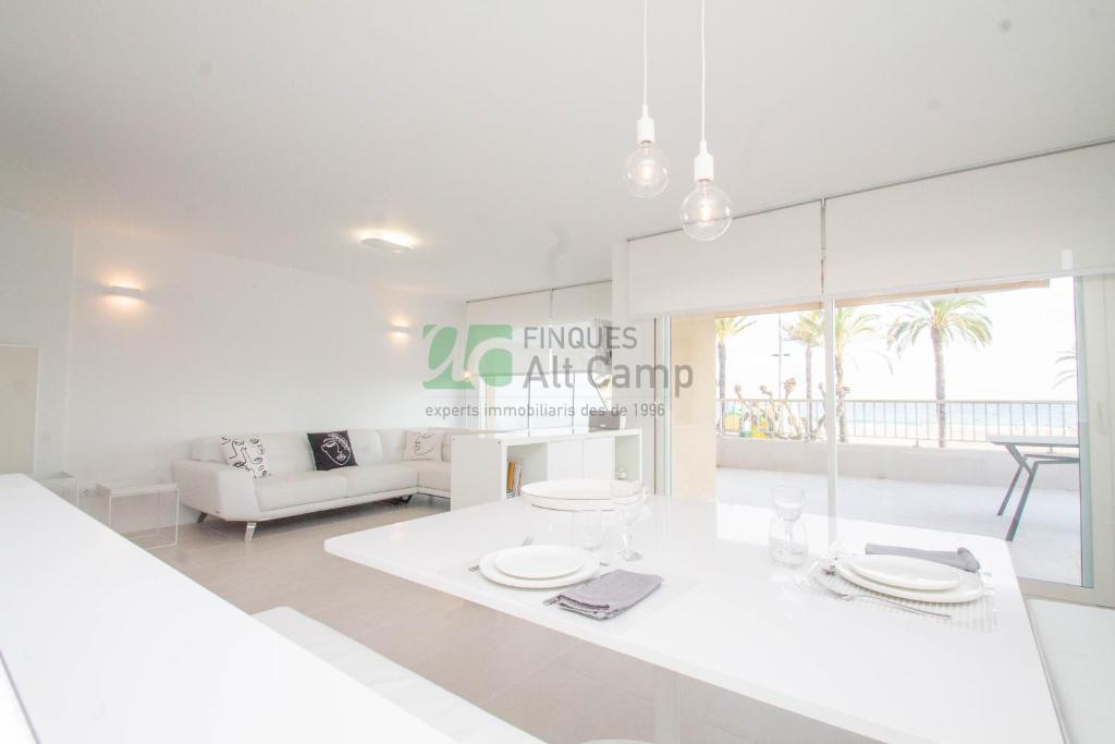 a white living room with a table and a couch at piso alto standing en Segur de Calafell in Calafell