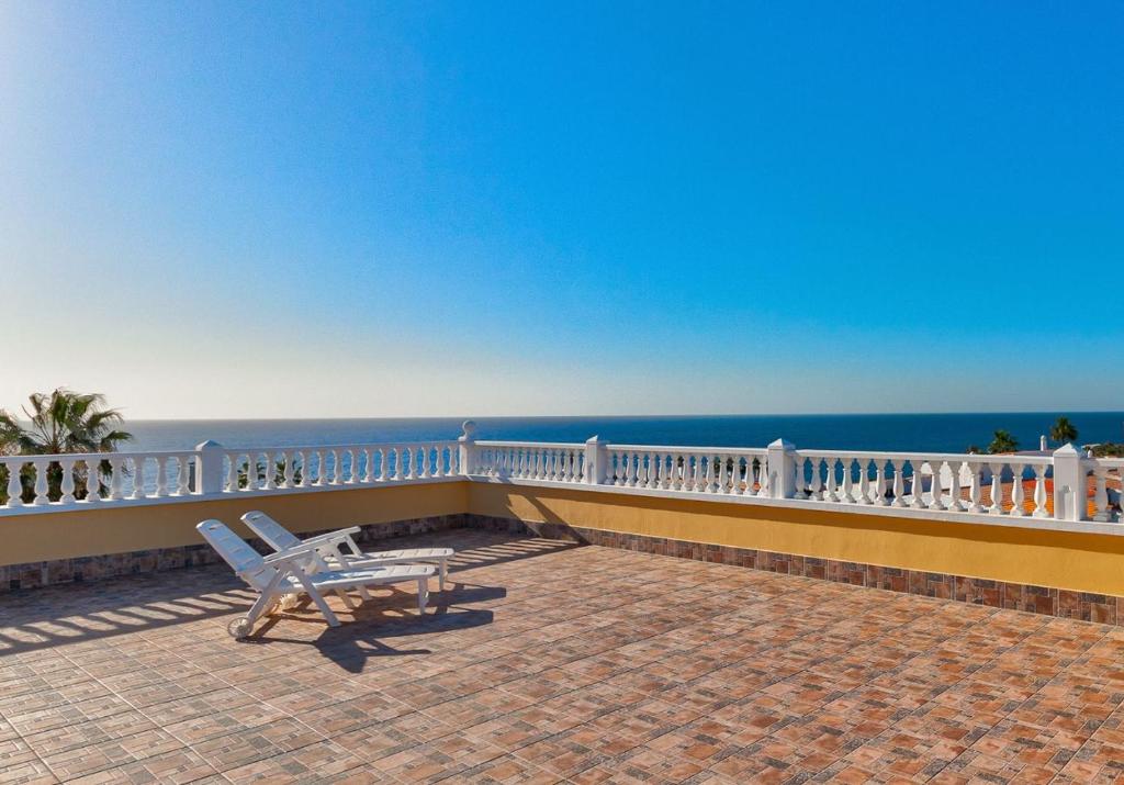 a white bench sitting on a balcony overlooking the ocean at Cozy two bedroom apartment in San Blas Golf del Sur Tenerife in San Miguel de Abona