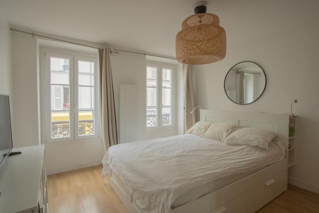 Habitación blanca con cama y espejo en Au petit gnolles - 450m Métro - 100m Parc en París