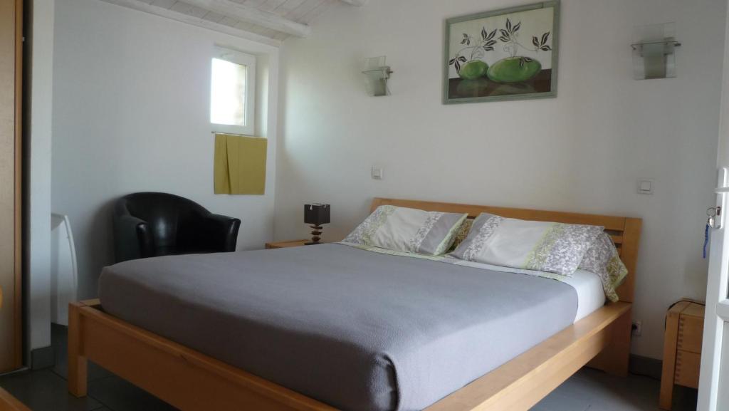 a bedroom with a bed and a black chair at Chambres d&#39;hôtes - Chez Stephane in L&#39;Ile d&#39;Yeu