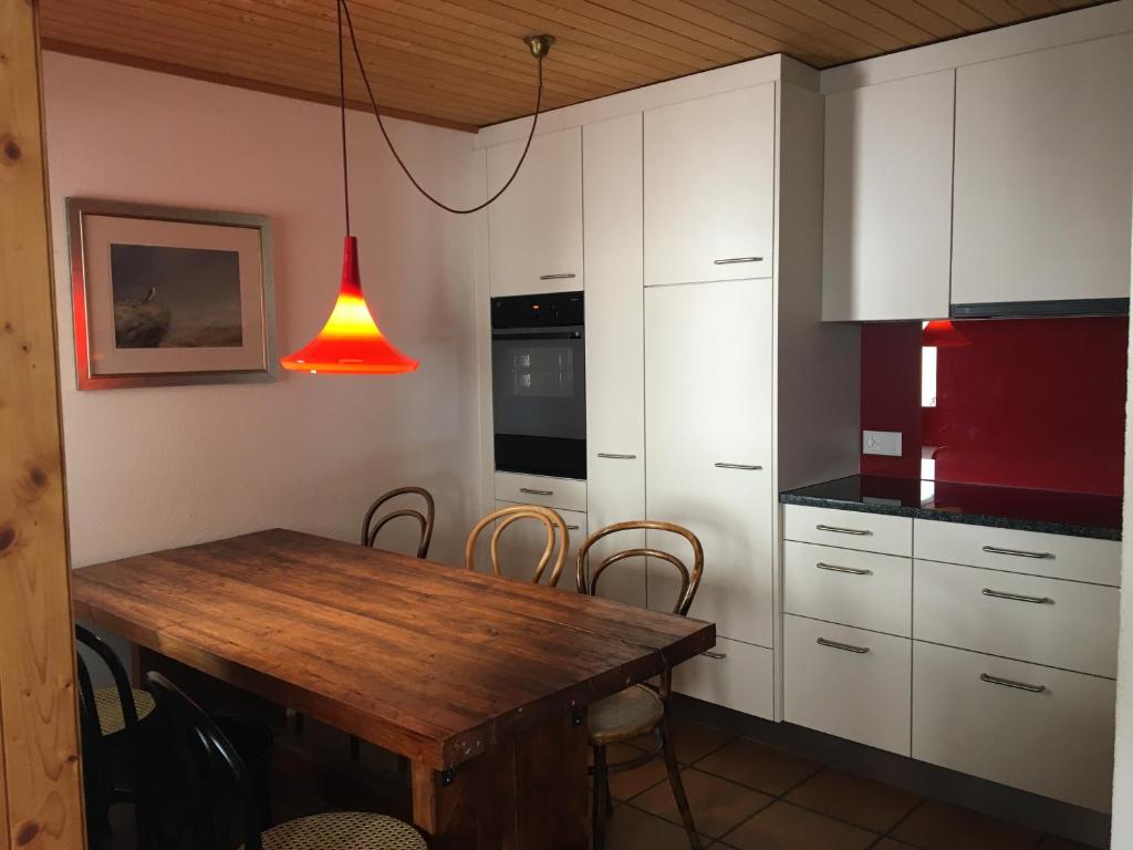 une cuisine avec une table en bois et une lumière rouge dans l'établissement Forigel UG, à Valbella