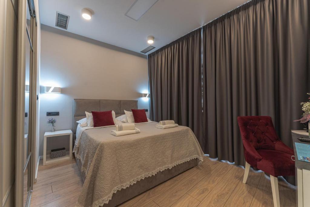 um quarto de hotel com uma cama e uma cadeira vermelha em Sky & Sun Luxury Rooms with private parking in the garage em Zadar