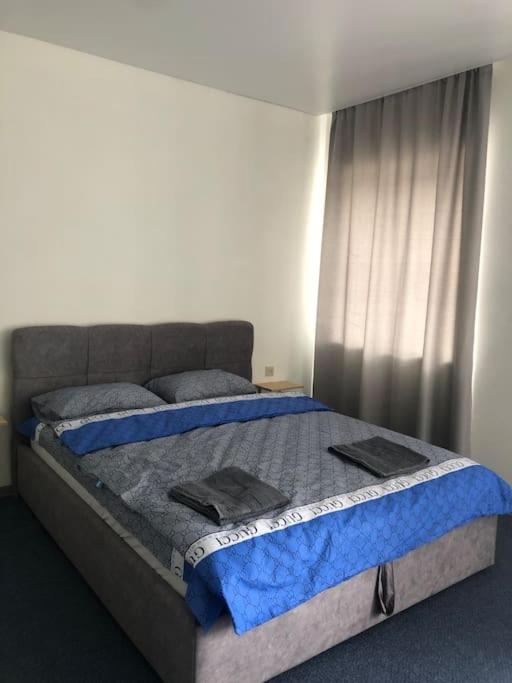 um quarto com uma cama com lençóis azuis e uma janela em Apartment on Zarwanska Street em Kamianets-Podilskyi