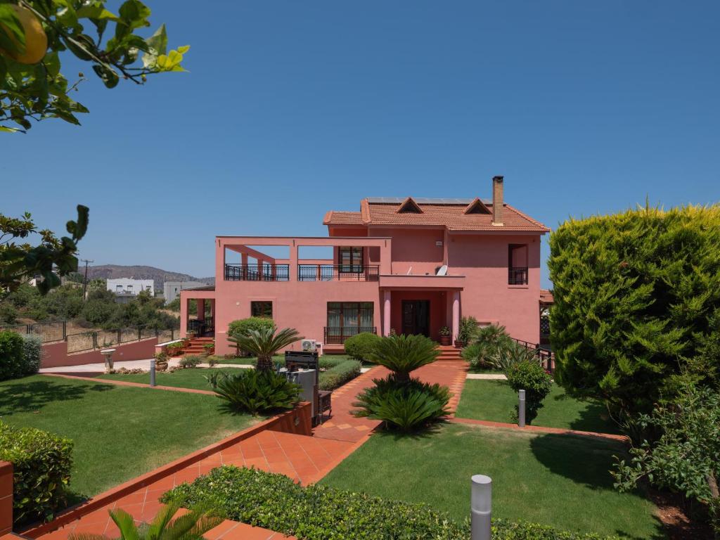 een roze huis met een tuin ervoor bij Villa Greco in Chersonissos