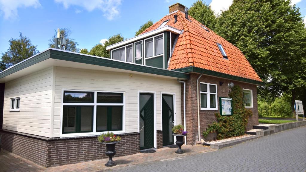 een klein huis met een oranje dak bij Het Kievitsnest in Oudehaske