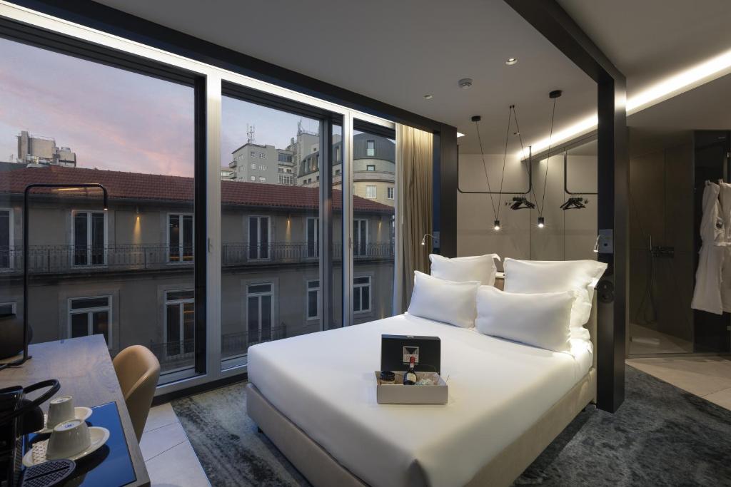 a bedroom with a large white bed and large windows at Porto Royal Bridges Hotel in Porto