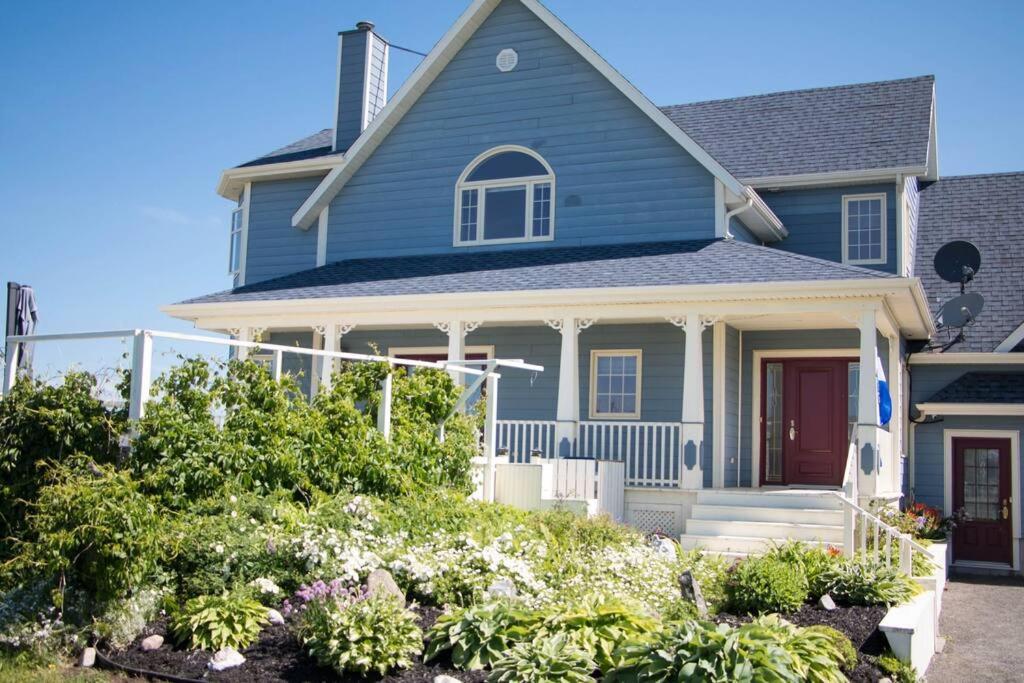 een blauw huis met bloemen ervoor bij Villa CARPE DIEM in Sainte-Flavie