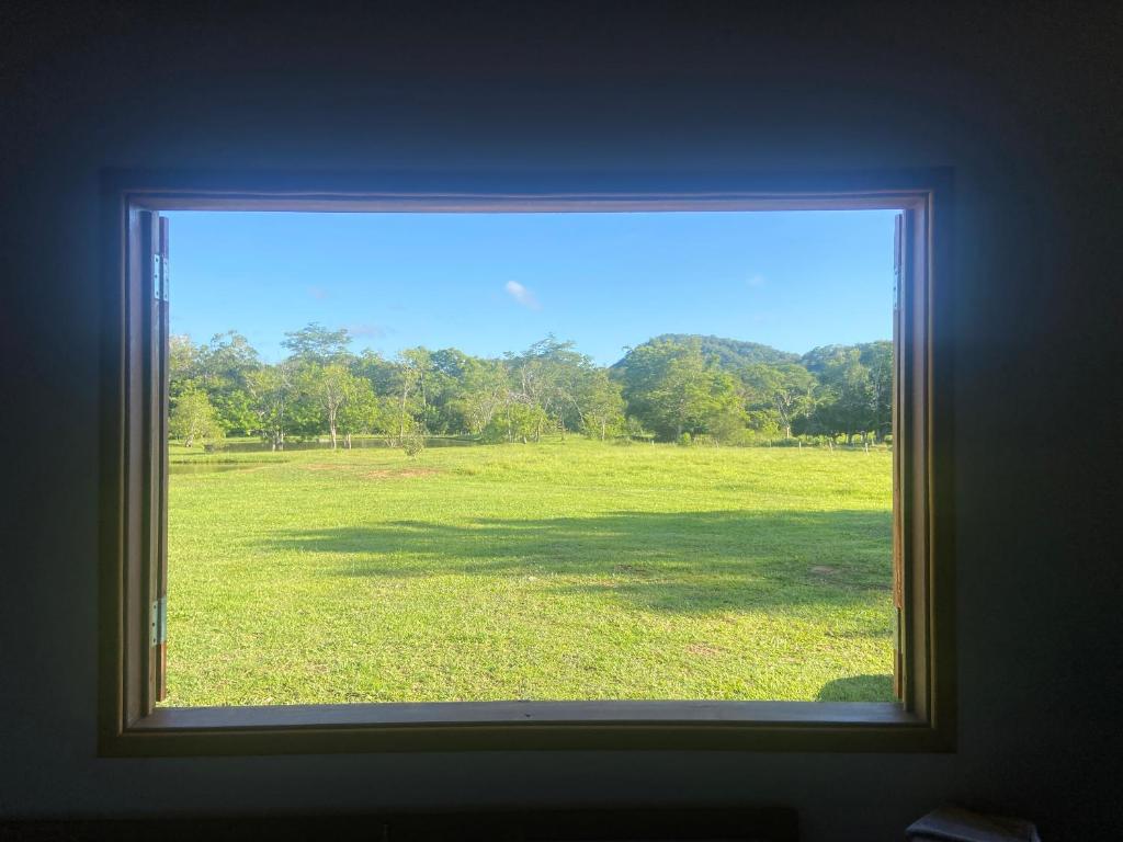 a window with a view of a field of grass at Refúgio Exclusivo no Meio da Natureza in Bonito