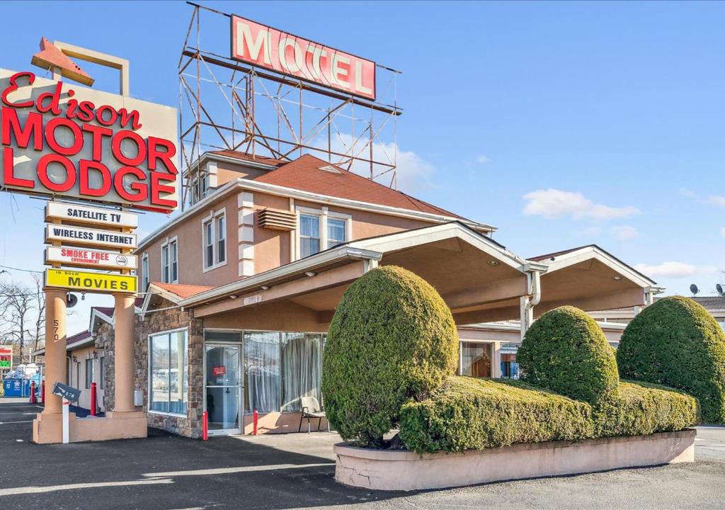 un motel con un cartel y arbustos delante de él en Edison Motor Lodge, en Edison